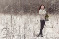 Beautiful red-haired girl in mittens walking with a lamp in a fabulous winter forest