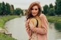 beautiful red-haired girl.picture against the background of the river, water, lake in the park, summer.hides his hat, embarrassmen Royalty Free Stock Photo