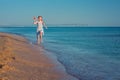 Beautiful red-haired girl, playing with toy airplane, runs along the sandy beach of the sea against the blue summer sky Royalty Free Stock Photo