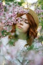 Beautiful red-haired girl posing and dreaming in spring almond flowers Royalty Free Stock Photo