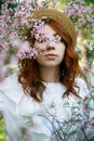 Beautiful red-haired girl posing and dreaming in spring almond flowers Royalty Free Stock Photo