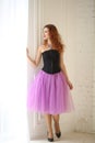 Girl in a purple tulle skirt and black corset is standing near the floor window Royalty Free Stock Photo