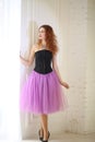 Girl in a purple tulle skirt and black corset is standing near the floor window Royalty Free Stock Photo