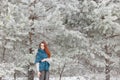 Beautiful red-haired girl with a scarf on his shoulders walking in the winter forest of firs and pines stilled Royalty Free Stock Photo