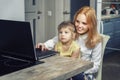 Beautiful red-haired girl teenager teaches her little sister to use a laptop