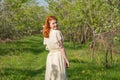 Beautiful red-haired girl walks in apple orchard Royalty Free Stock Photo