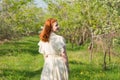 Beautiful red-haired girl walks in apple orchard Royalty Free Stock Photo