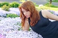 Beautiful red haired lady in a black dress smelling flowers Royalty Free Stock Photo