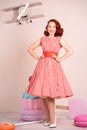 Beautiful red-haired pinup smiling happily girl posing in a retro red dress and white high heels Royalty Free Stock Photo