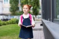 beautiful red haired schoolgirl with backpack holding