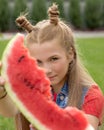 Beautiful red-haired teen girl shows a large piece of juicy red watermelon. healthy food, vitamins and diet. Summer time, outside Royalty Free Stock Photo