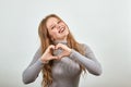 Beautiful red-haired woman in gray sweater tilts head and smiles with happiness