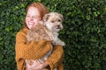 Beautiful red-haired woman has her little dog in her arms Royalty Free Stock Photo
