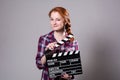 Beautiful red-haired woman holding a movie clapper, isolated over gray background Royalty Free Stock Photo