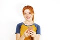 Beautiful red headed young woman posing, showing emotional facial expressions and making funny faces with mobile phone Royalty Free Stock Photo