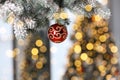 Beautiful red holiday bauble hanging on Christmas tree against blurred fairy lights, closeup Royalty Free Stock Photo