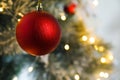 Beautiful red holiday bauble hanging on Christmas tree against blurred fairy lights, closeup. Space for text Royalty Free Stock Photo