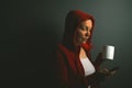 Beautiful red hooded woman drinking coffee and sending text mess