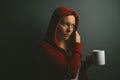 Beautiful red hooded woman drinking coffee and using mobile phon