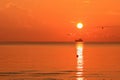 Beautiful red orange sunrise above the sea and clouds with a ship crossing the reflected in the water sun path Royalty Free Stock Photo