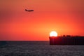 Beautiful red and orange sunset over the sea. The sun goes down over the sea. Red sunset with landing silhouette airplane. Royalty Free Stock Photo