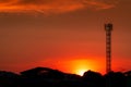 Beautiful red and orange sunset sky. Silhouette telecommunication tower and tree in the evening with beautiful red sunset sky