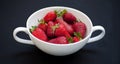 Red, juicy, ripe strawberries on a white bowl and black background Royalty Free Stock Photo