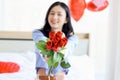 Beautiful red rose bouquet on Asian woman hand, happy girl showing Valentine flower present from lover boyfriend to camera while