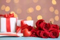 Beautiful red roses, decorative heart, love letter and gift boxes on table against blurred lights, space for text. St. Valentine` Royalty Free Stock Photo