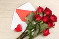 Beautiful red roses, envelope with love letter and decorative heart on white wooden background, flat lay. Valentine`s Day Royalty Free Stock Photo