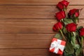Beautiful red roses and gift box on wooden background, flat lay with space for text. Valentine`s Day celebration Royalty Free Stock Photo