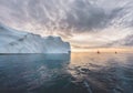 Beautiful red sailboat in the arctic next to a massive iceberg showing the scale. Cruising among floating icebergs in