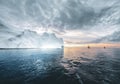 Beautiful red sailboat in the arctic next to a massive iceberg showing the scale. Cruising among floating icebergs in