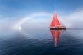 Beautiful red sailboat under a glowing fog bow. Royalty Free Stock Photo