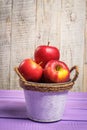 Beautiful red sweet apples on a white and purple background in a white bucket Royalty Free Stock Photo