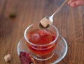 Beautiful red tea. Berry tea with red leaves on a blurred background. Woman with a spoon of sugar and a cup. Copy space.