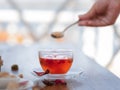 Beautiful red tea. Berry tea with red leaves on a blurred background. Woman with a spoon of sugar and a cup. Copy space.