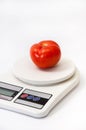 Beautiful red tomato on a white kitchen scale Royalty Free Stock Photo