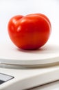 Beautiful red tomato on a white kitchen scale Royalty Free Stock Photo