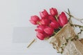 Beautiful red tulips in craft paper with greeting card, pencil, scissors on white wood. Mothers day Royalty Free Stock Photo