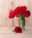 Beautiful red tulips in glass vase on table on a wooden background with space for text Royalty Free Stock Photo