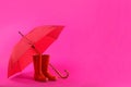 Beautiful red umbrella and rubber boots on pink background Royalty Free Stock Photo