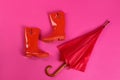 Beautiful red umbrella and rubber boots on background, flat lay Royalty Free Stock Photo