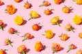 Beautiful red and yellow roses arranged in a pattern on a pastel pink background.
