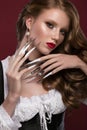 Beautiful redhair model: curls, bright gold makeup, long nails and red lips. The beauty face. Manicure disign