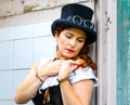 Beautiful redhair steampunk girl with goggles on black hat outside toilet background. Old-fashioned Royalty Free Stock Photo