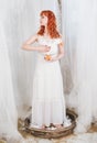 Beautiful redhaired woman with goose toy standing in the nest Easter holiday concept