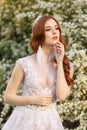 Beautiful redhead Bride in fantastic wedding dress in blooming garden. Royalty Free Stock Photo