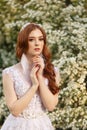 Beautiful redhead Bride in fantastic wedding dress in blooming garden. Royalty Free Stock Photo