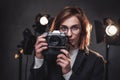 Beautiful redhead female photographer holds a digital camera and looking on the camera Royalty Free Stock Photo